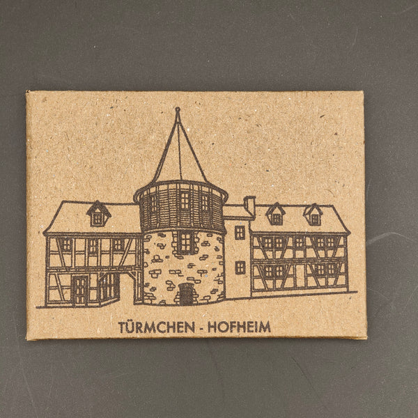 Kraft paper card with a printed illustration of a half-timbered house and text on a gray background